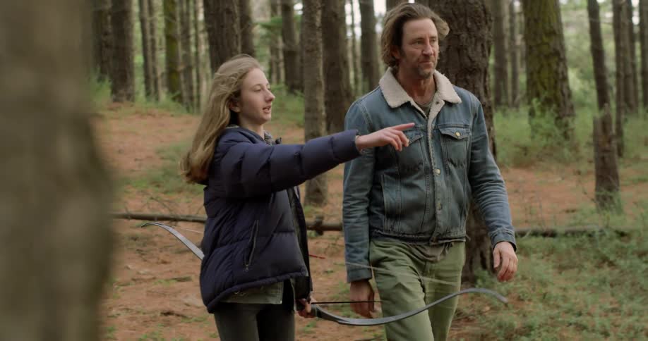 A girl with a bow walks in the forest and points something out