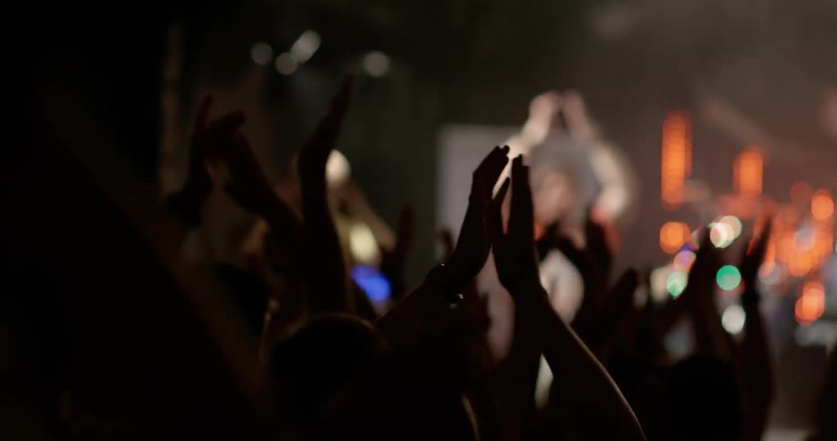 People dance and clap in a dance club