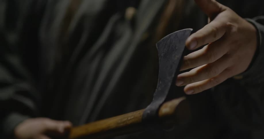 A man is testing the sharpness of his axe