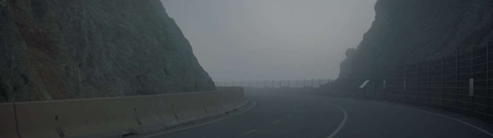 A road curve is shown on a foggy day