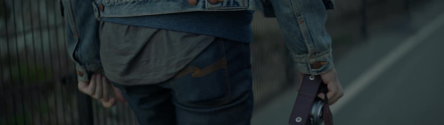 A man carries a camera down the street
