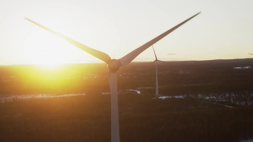 Three wind turbines are spinning with the sun in the background