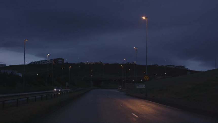 A dark street at night with lamp posts above