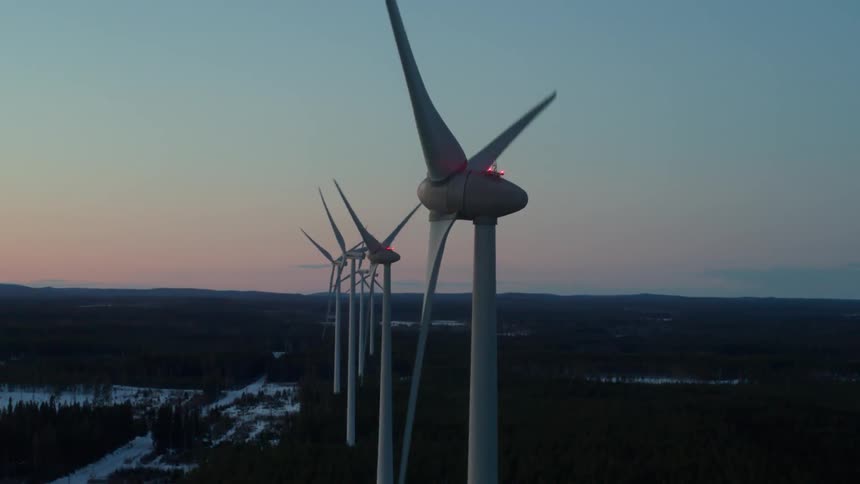 Spinning windmills in a row at sunset