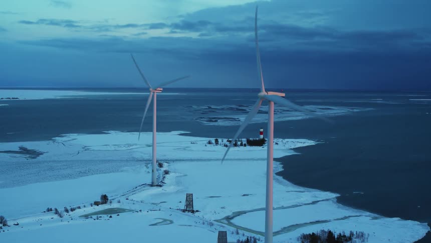 Wind turbines are spinning above snow covered ground