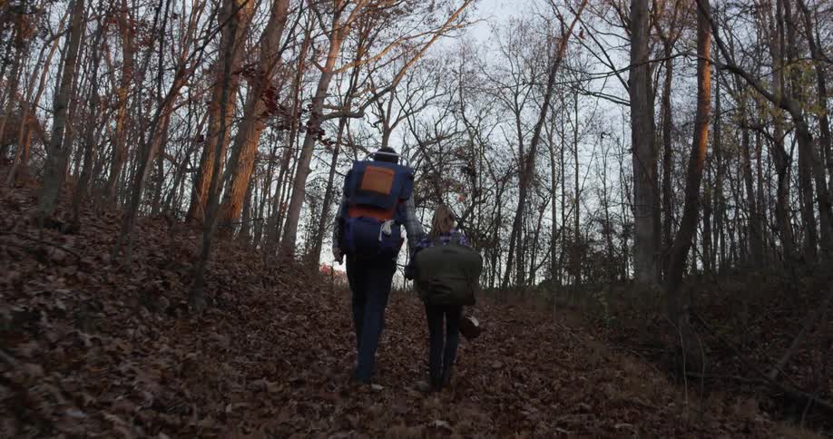 A man is hiking in a forest with a young girl on an autumn day