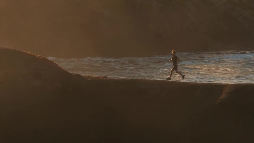 A man runs along the coast at sunset