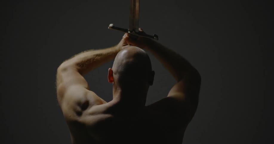 A bald man raises a sword above his head
