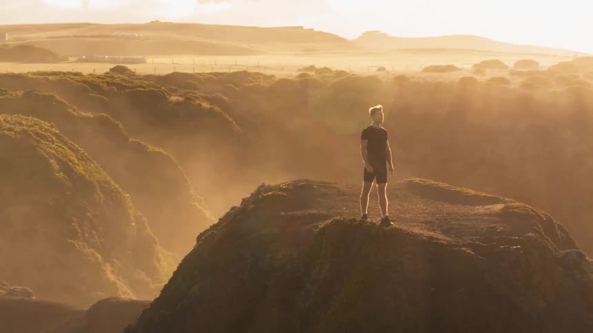A man is standing on top of a cliff