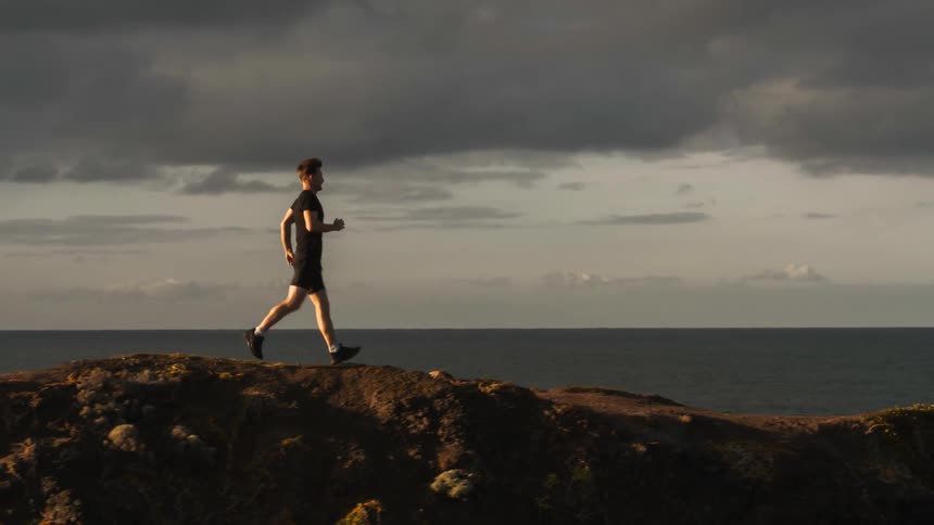 A man is running along the edge of a cliff