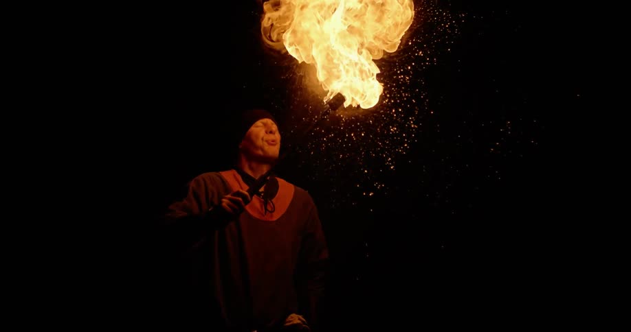 A man spits fuel onto a torch and ignites it