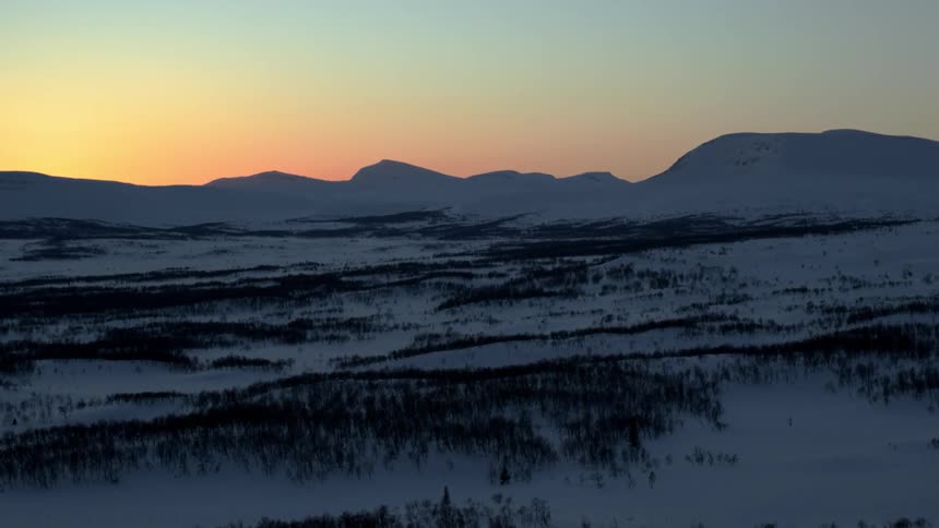 Mountains stand next to a field of trees