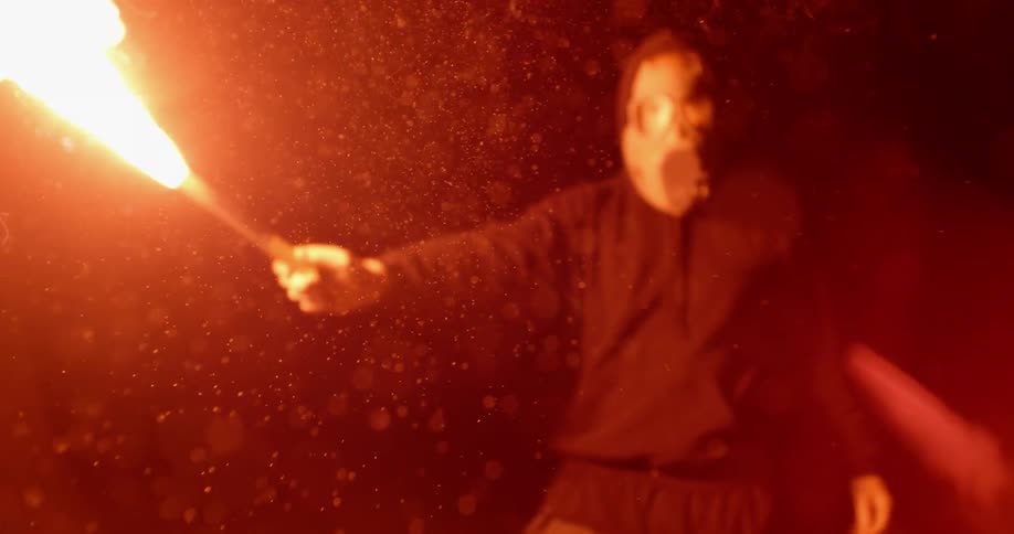 A man wearing a gas mask holds a lit flare