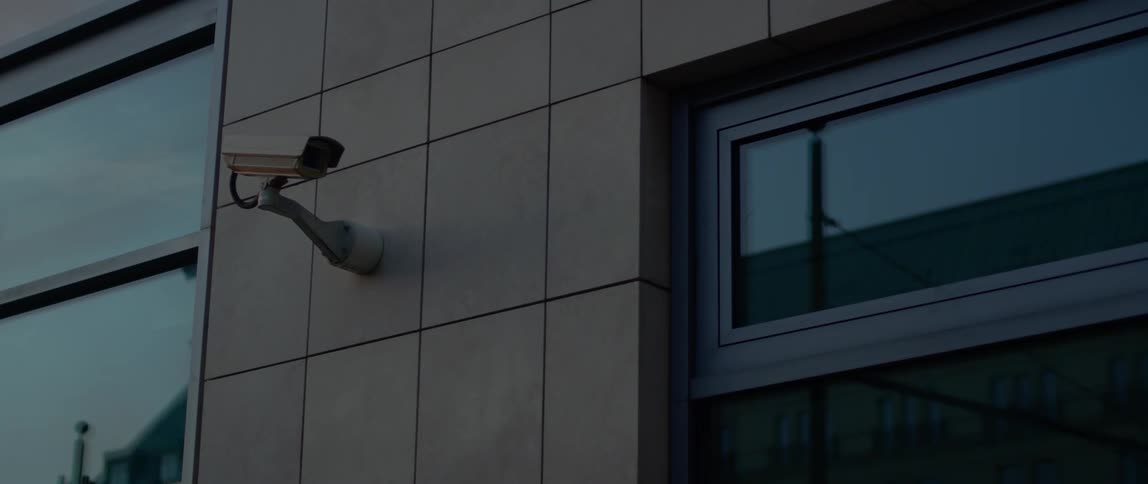 A security camera is attached to the exterior of a building