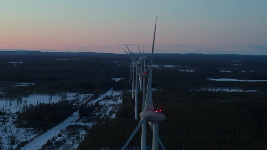 Wind turbines are spinning above a frozen landscape