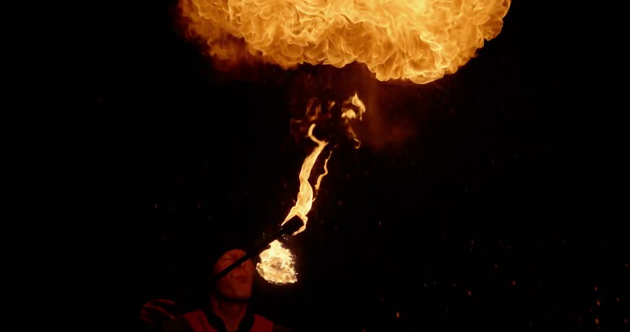 A man blows on a torch and a fire explodes