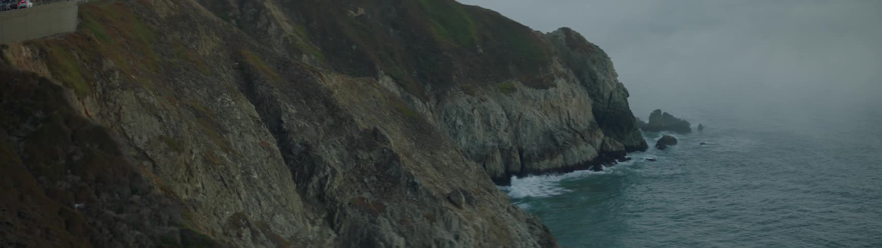 Waves crash into the base of a mountain