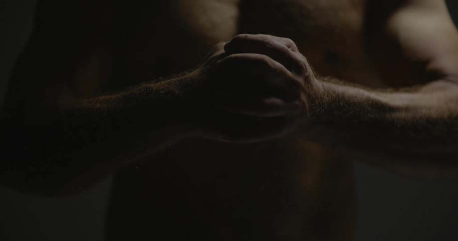 Shirtless man pounding his fist into his other hand