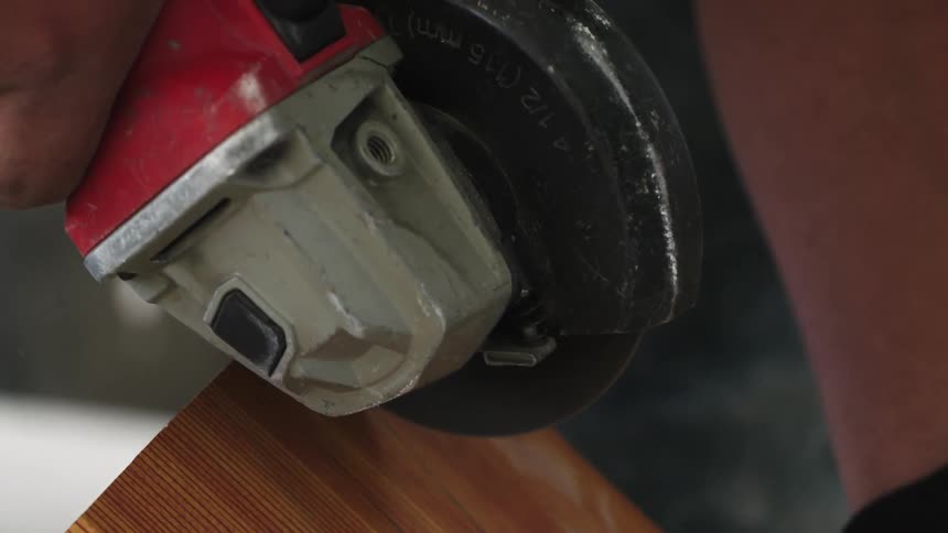 A man is grinding a piece of wood