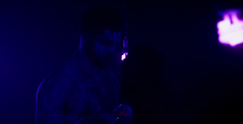 A man and woman are covered in glowing body paint in a dimly lit room