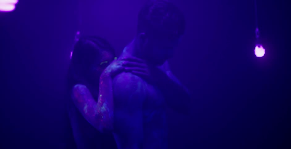 A man and woman dance covered in colored paint