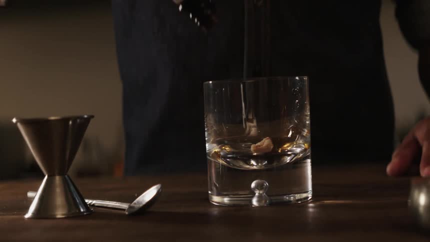 A bartender prepares a drink in a glass