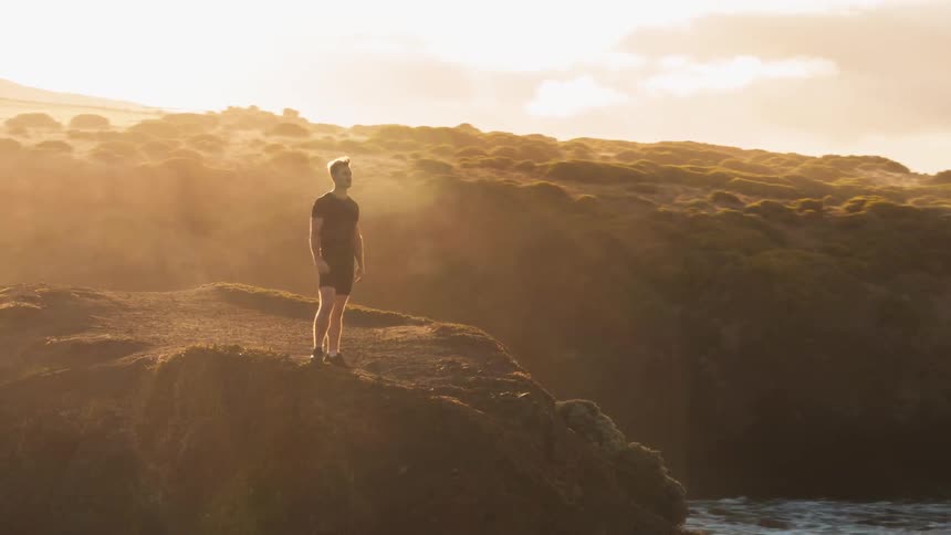 A man stands atop a mountain
