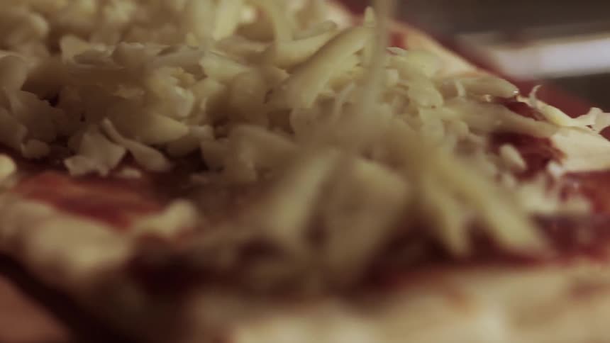 Cheese shreds are put on a pizza