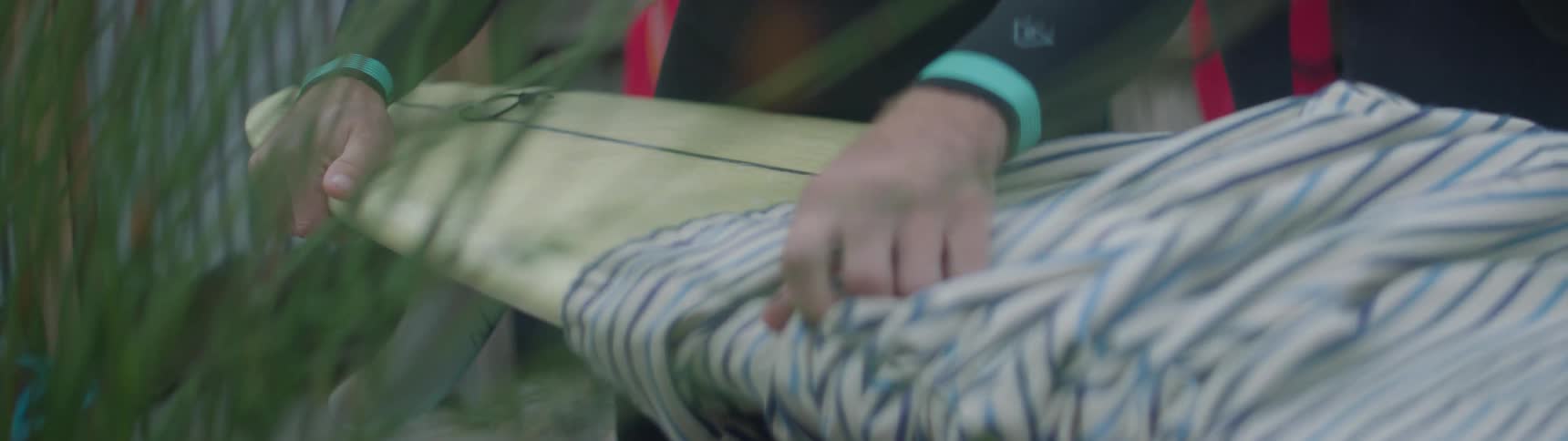 A surfer removes a surfboard from a protective covering
