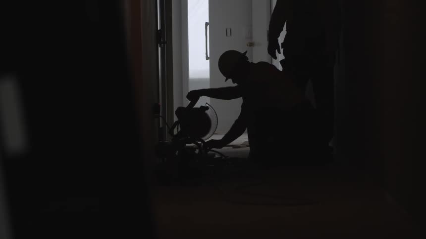 Two people check out power tools in a dark hallway