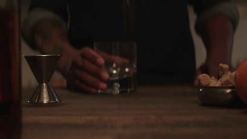 A bartender places an empty glass in front of him