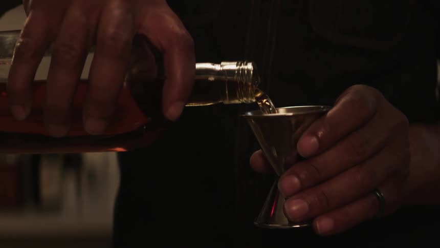A man is pouring whiskey into a jig