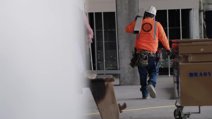A construction worker carries materials on a job site