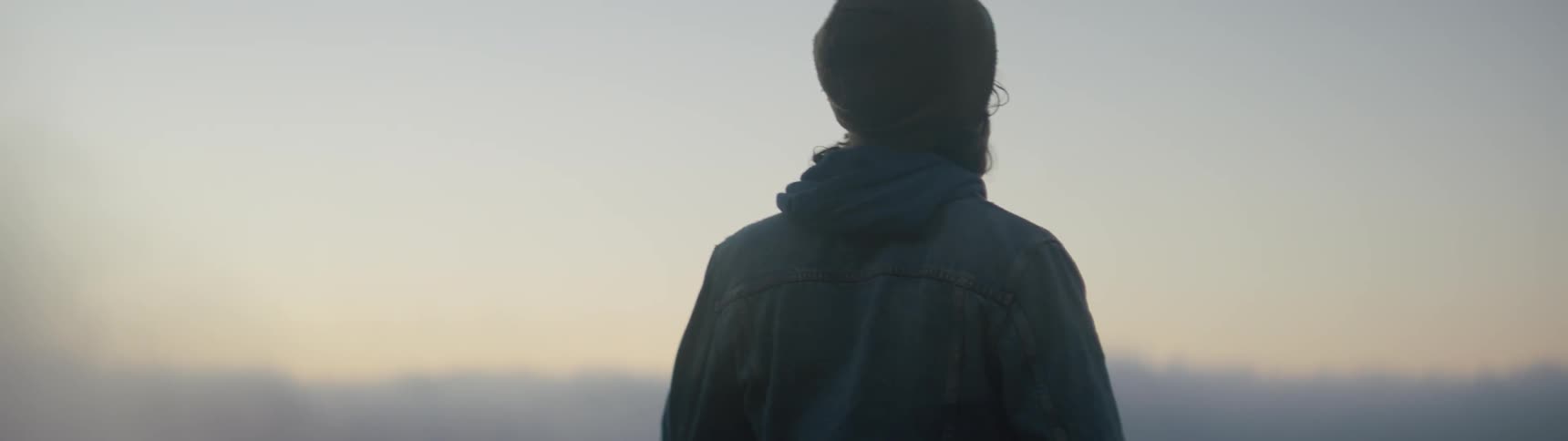 Man wearing a jacket and a toque looks off into the distance