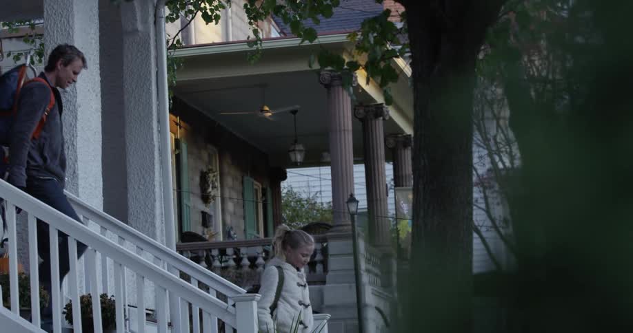 A woman is kidding her kid goodbye on the porch