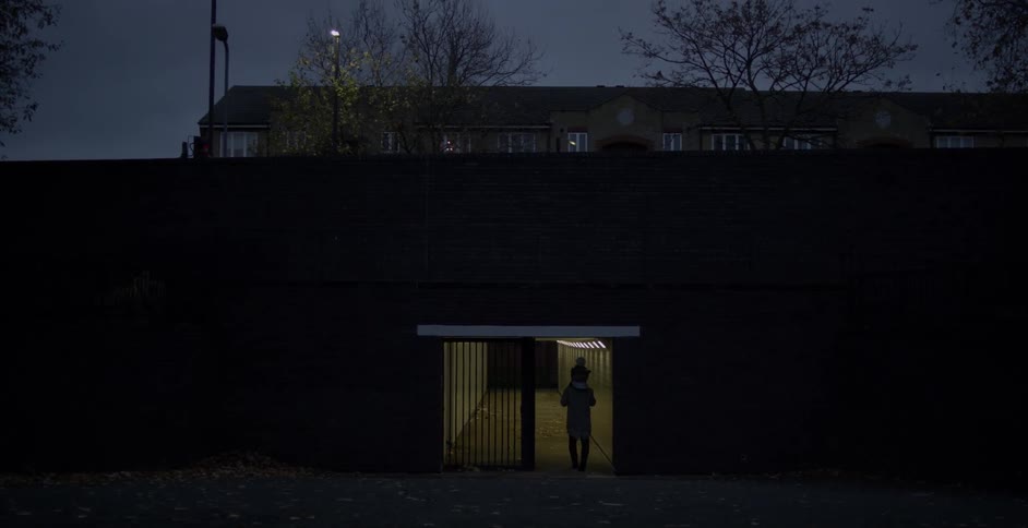 A man carries a child on his shoulder towards a tunnel