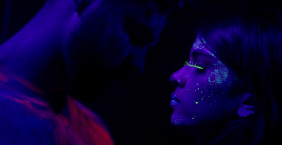 A woman and man touch with glowing body paint
