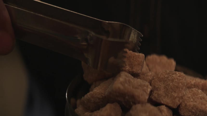 Metal tongs are used to pick up sugar cubes
