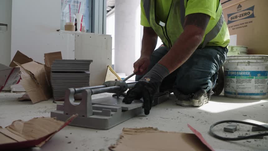 Man trims a square of tile