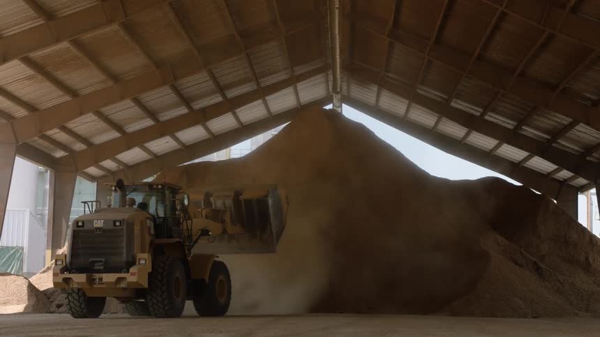 A tractor pushes dirt onto a large pile and backs away