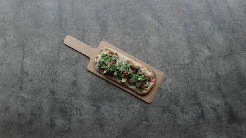 A pizza sits on a wood pizza peel