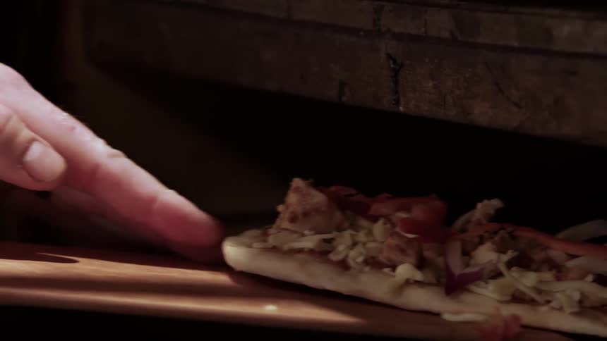A pizza is put into the oven to cook