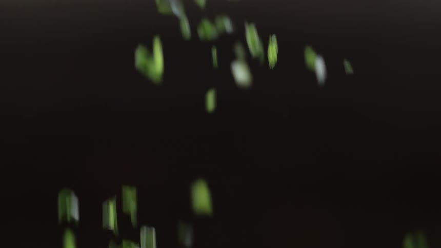 A hand sprinkles chopped green herbs