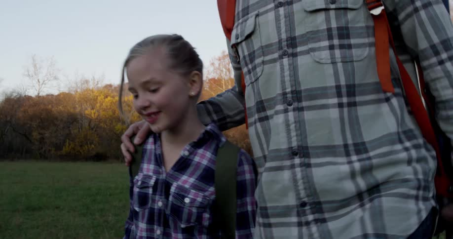 A young girl smiles and talks as she hikes with a male companion