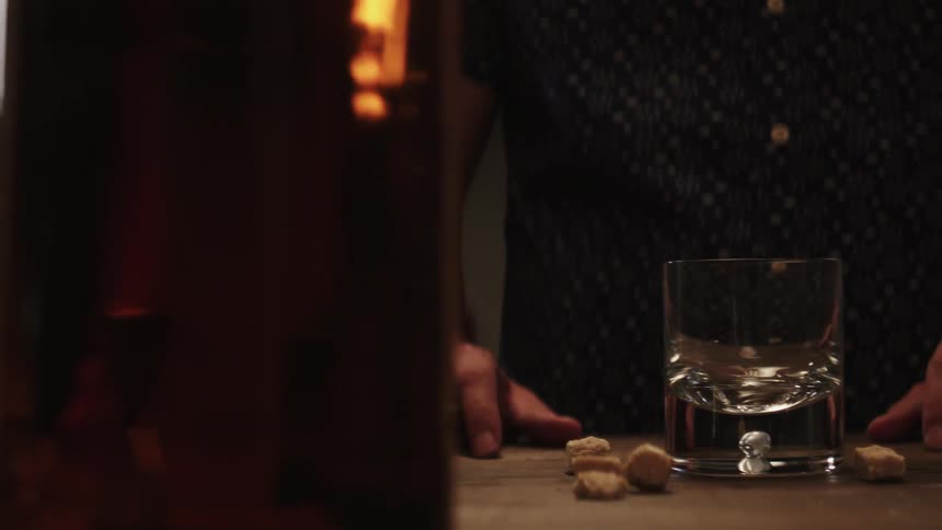 A man is standing near a table with a glass and other ingredients