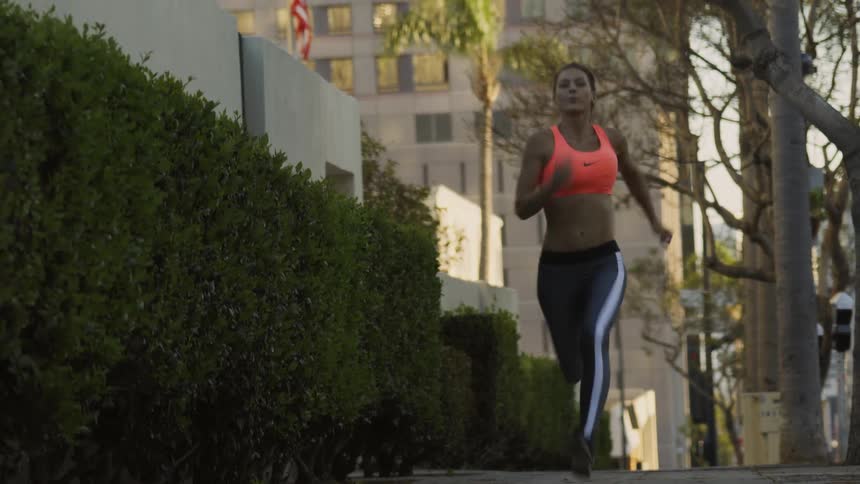 A woman runs on a city sidewalk