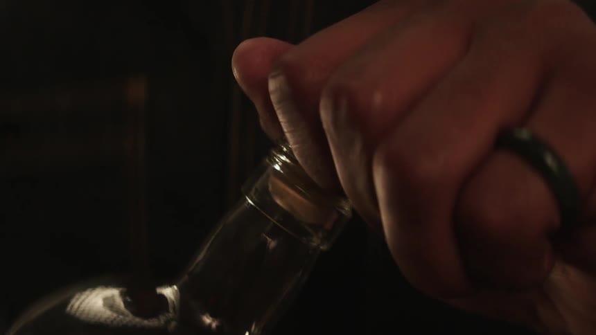 A man is opening a bottle of whiskey