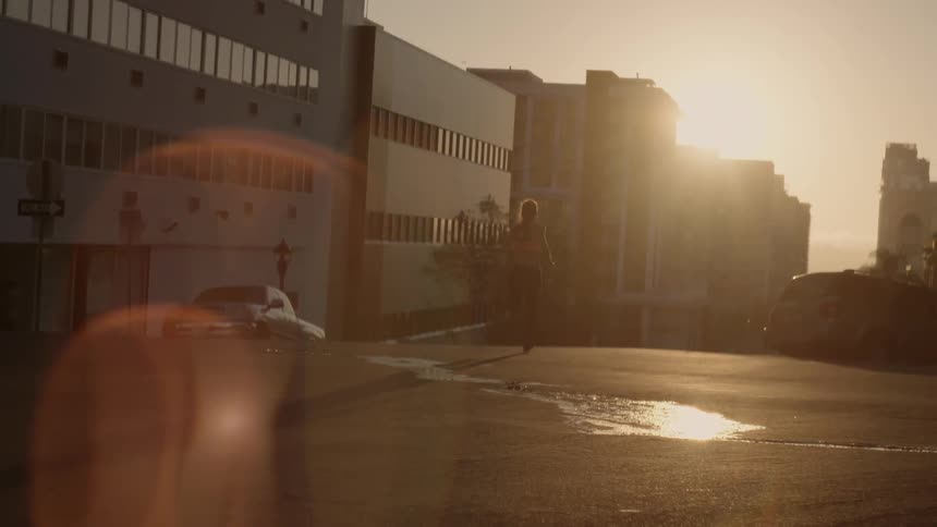 A woman runs down the street at dawn