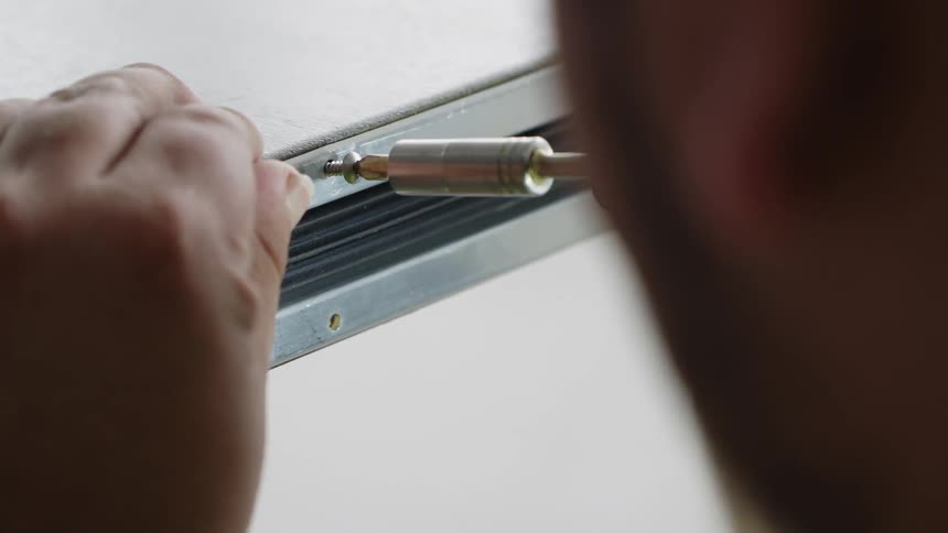 A worker drills a screw in place