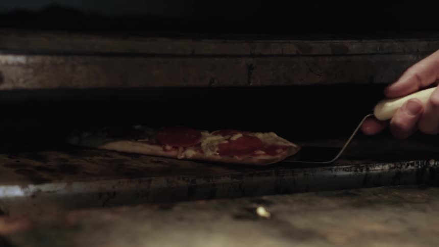 A chef rotates a pizza in the oven